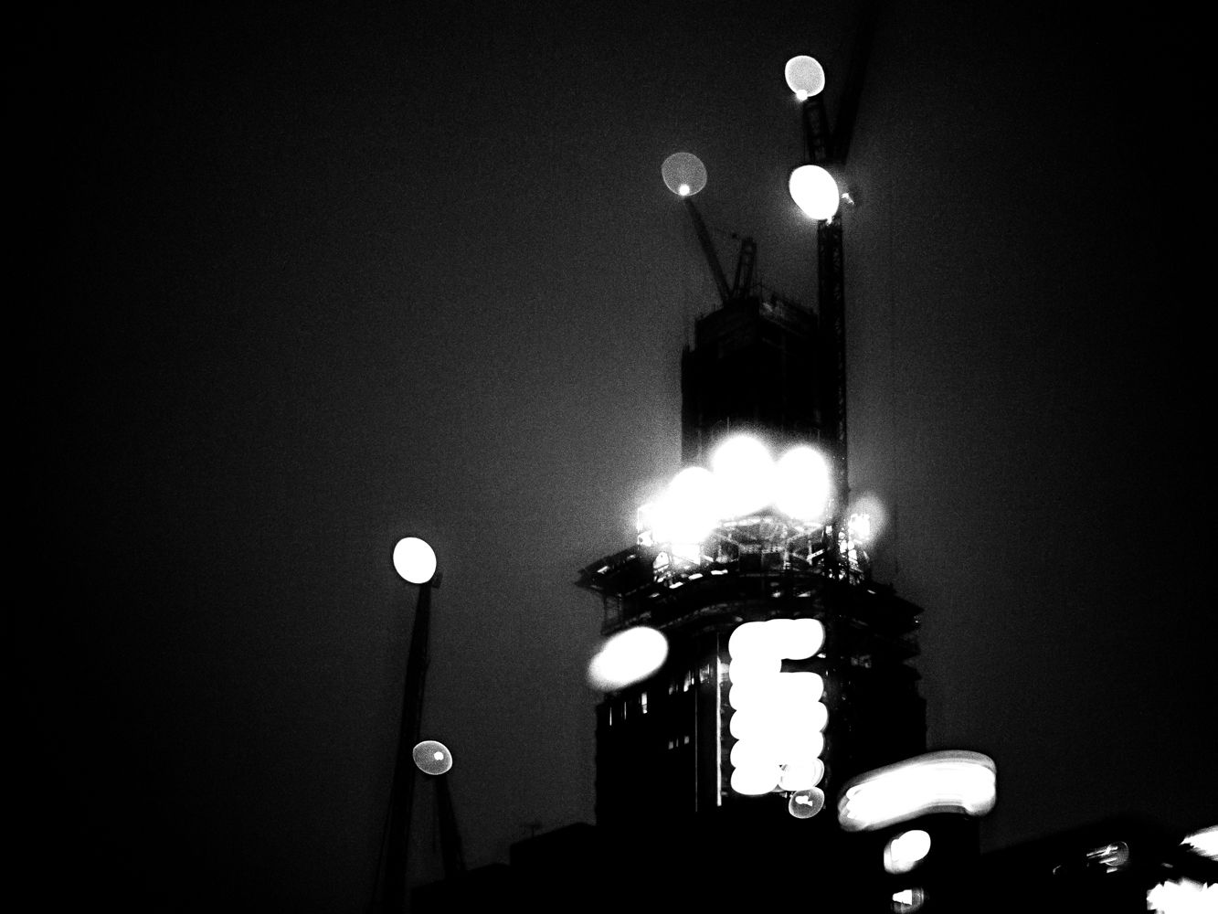 Blurry black and white image of tall building under construction.