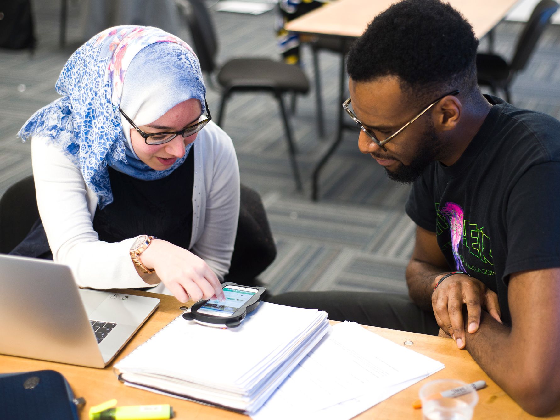 Students looking at app on phone screen.