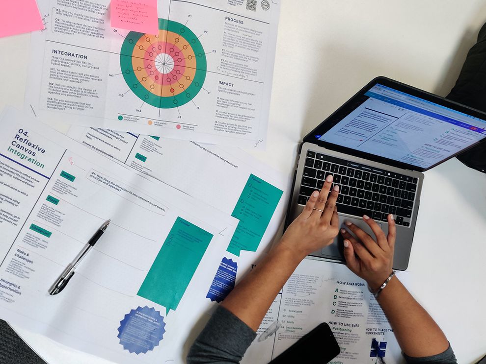 Image of a laptop sitting on a table of notes.