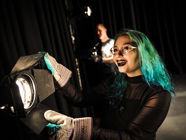 Green-haired girl operating a stage light