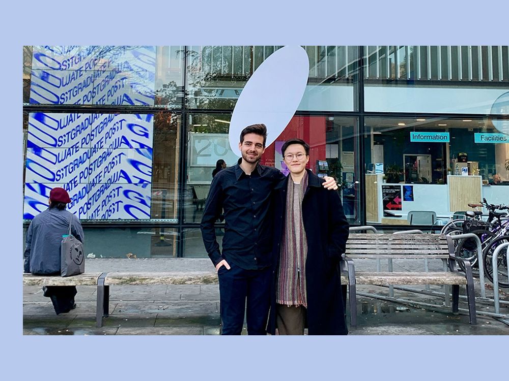 Two people stand outside an art exhibition.