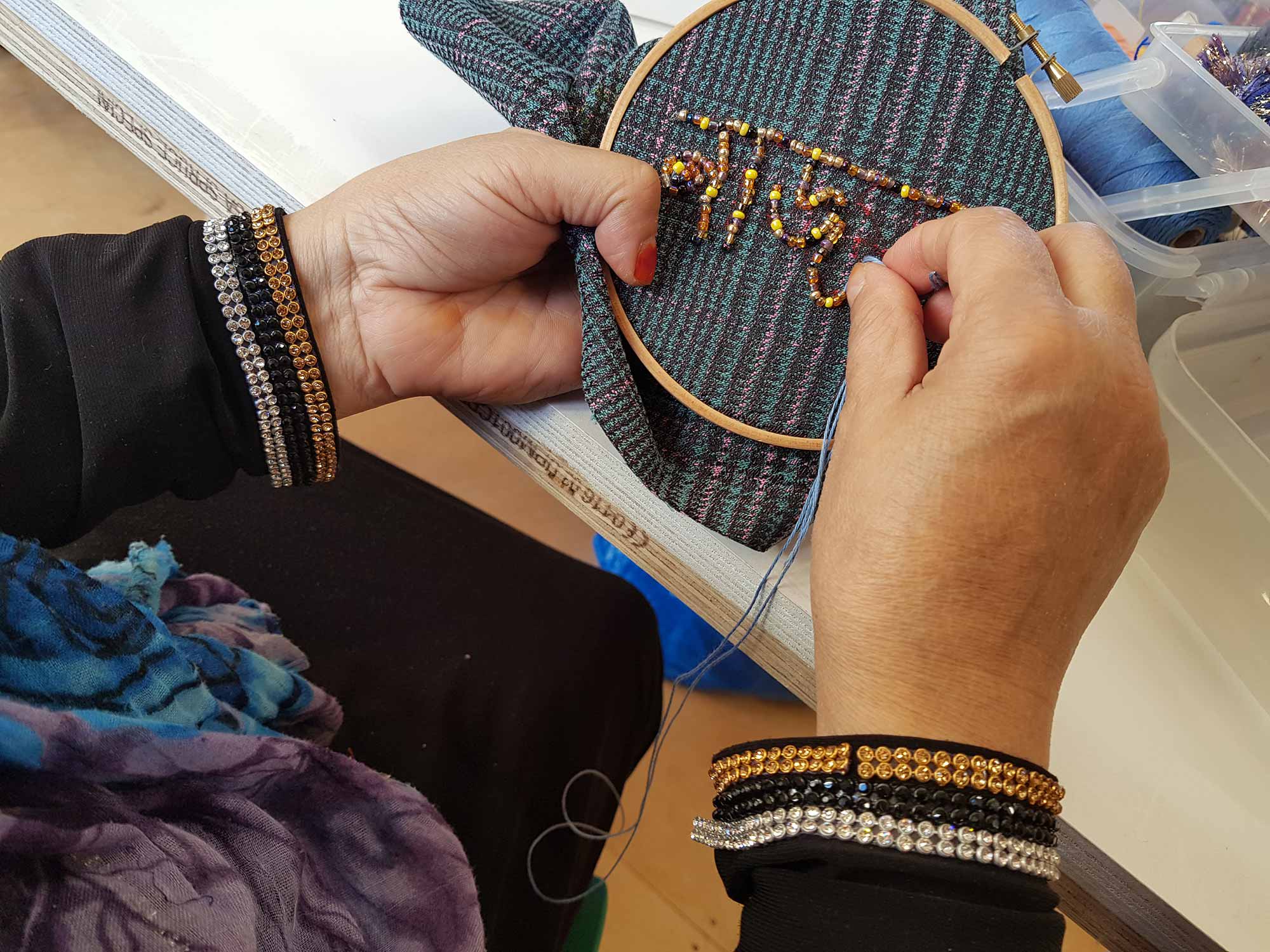 Hand sewing beads into fabric