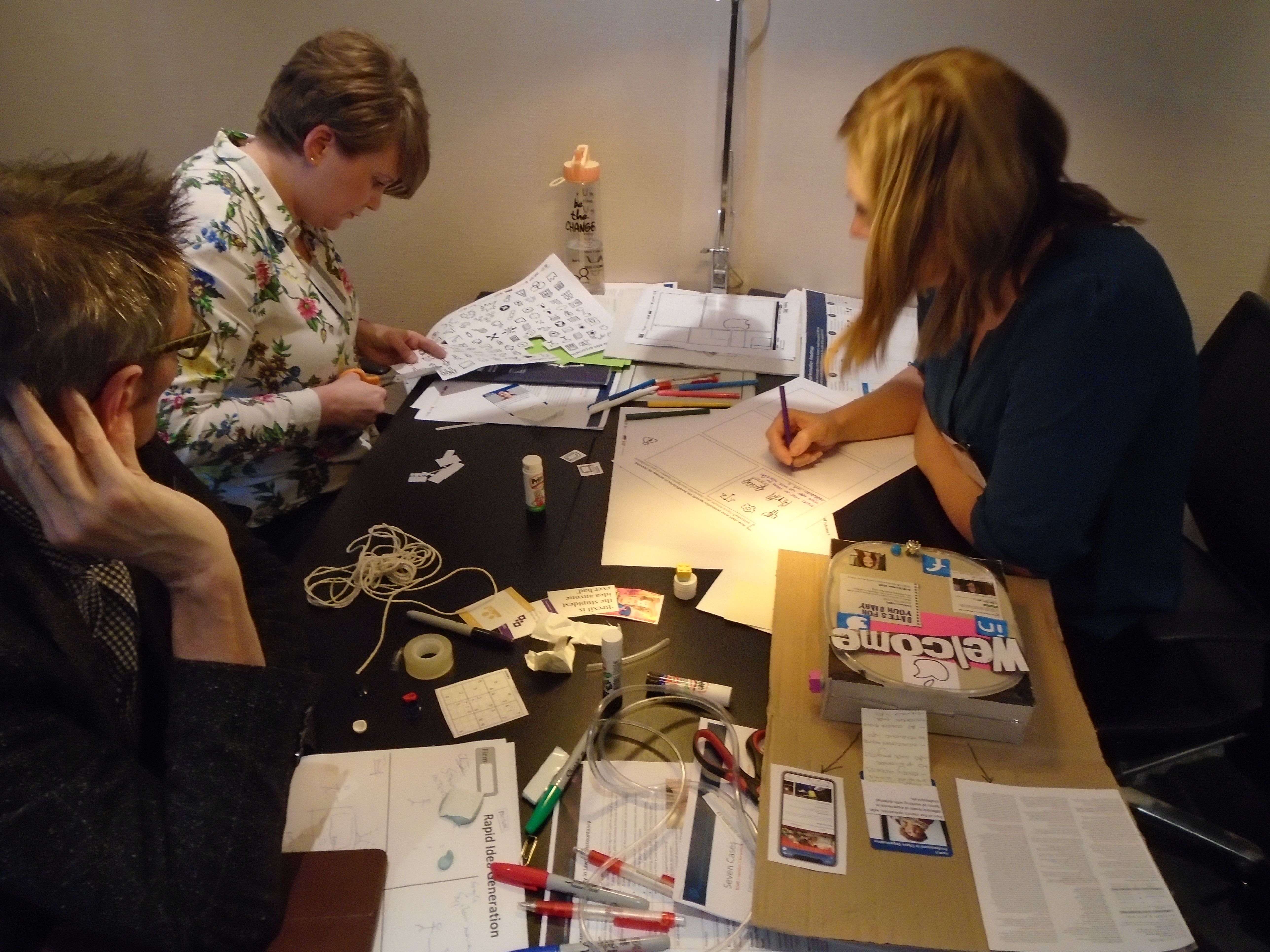 People working at a table with lots of papers and materials on the desk
