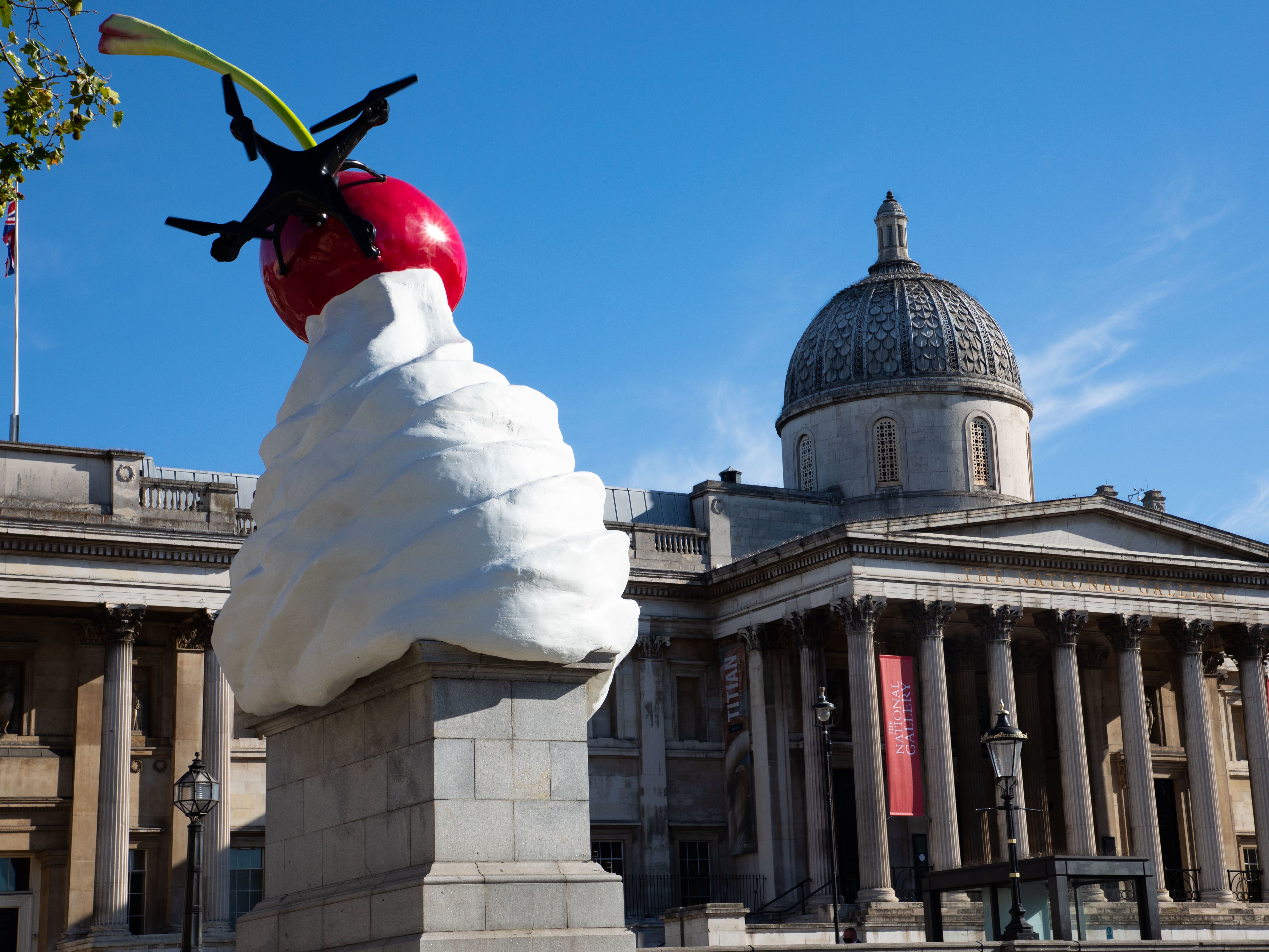 A sculpture of an ice cream with a cherry in it on top of a plinth in Trafalgar Square