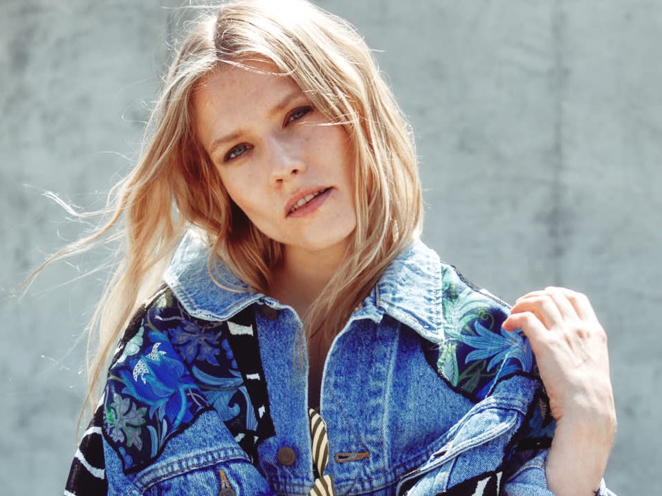 Model wearing an upcycled denim jacket with zebra print arm panels and patchwork accents.