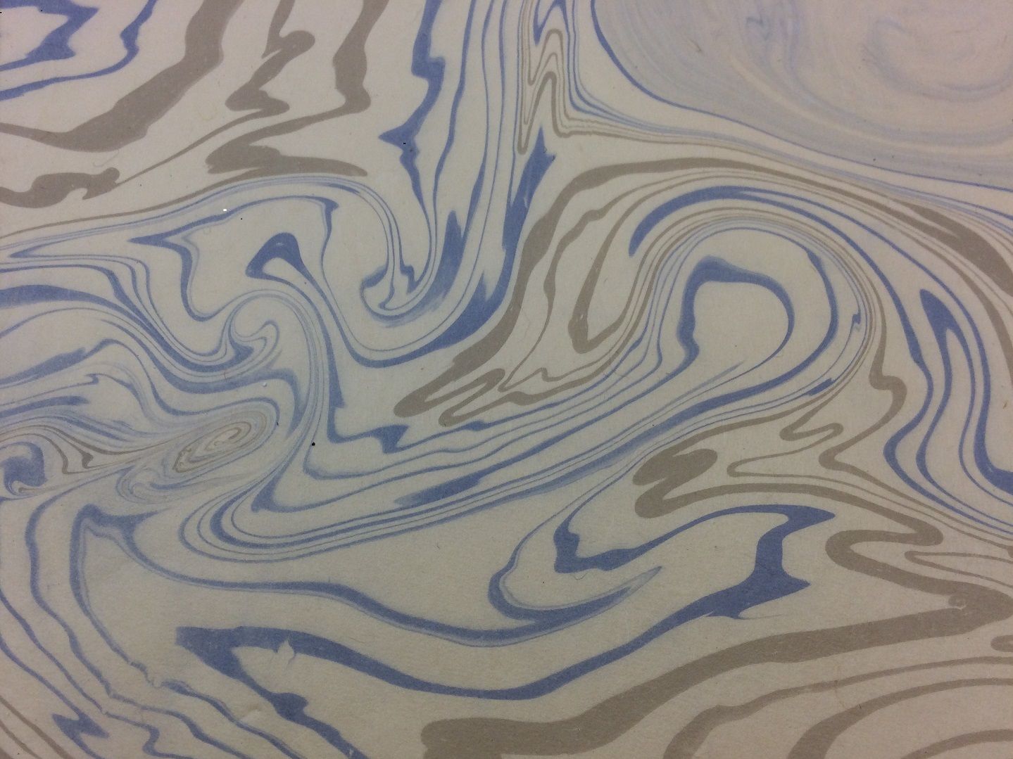 A piece of marbled paper with swirls of blue and grey