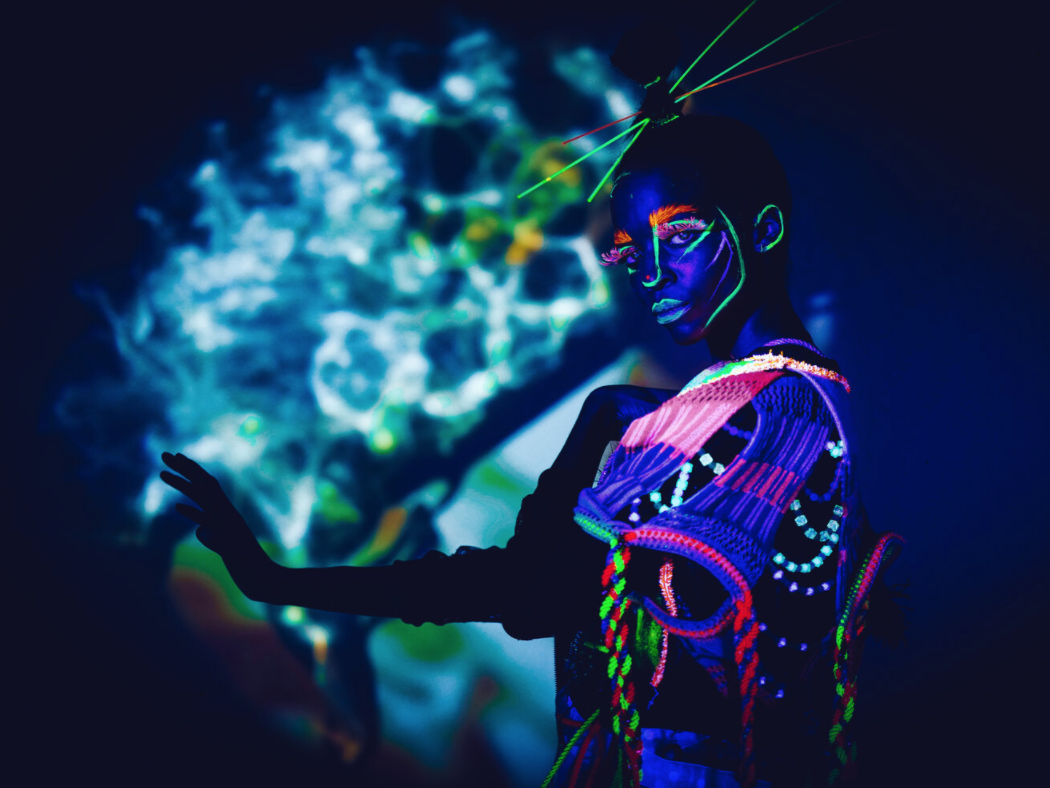 Girl in the dark in a glowing neon dress and makeup 