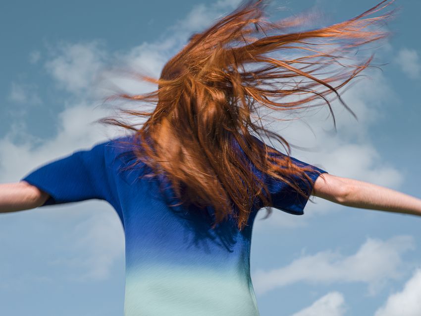 A person wearing a blue woollen outfit, standing in front of the sky 