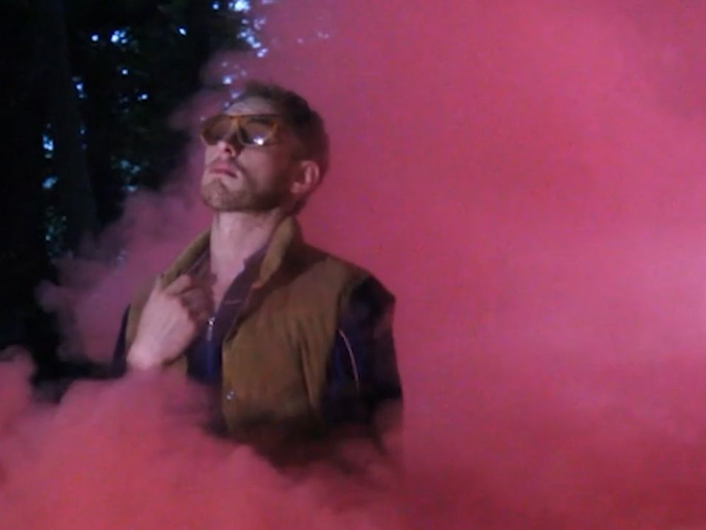 Luke Abbott stood among red smoke wearing sunglasses.