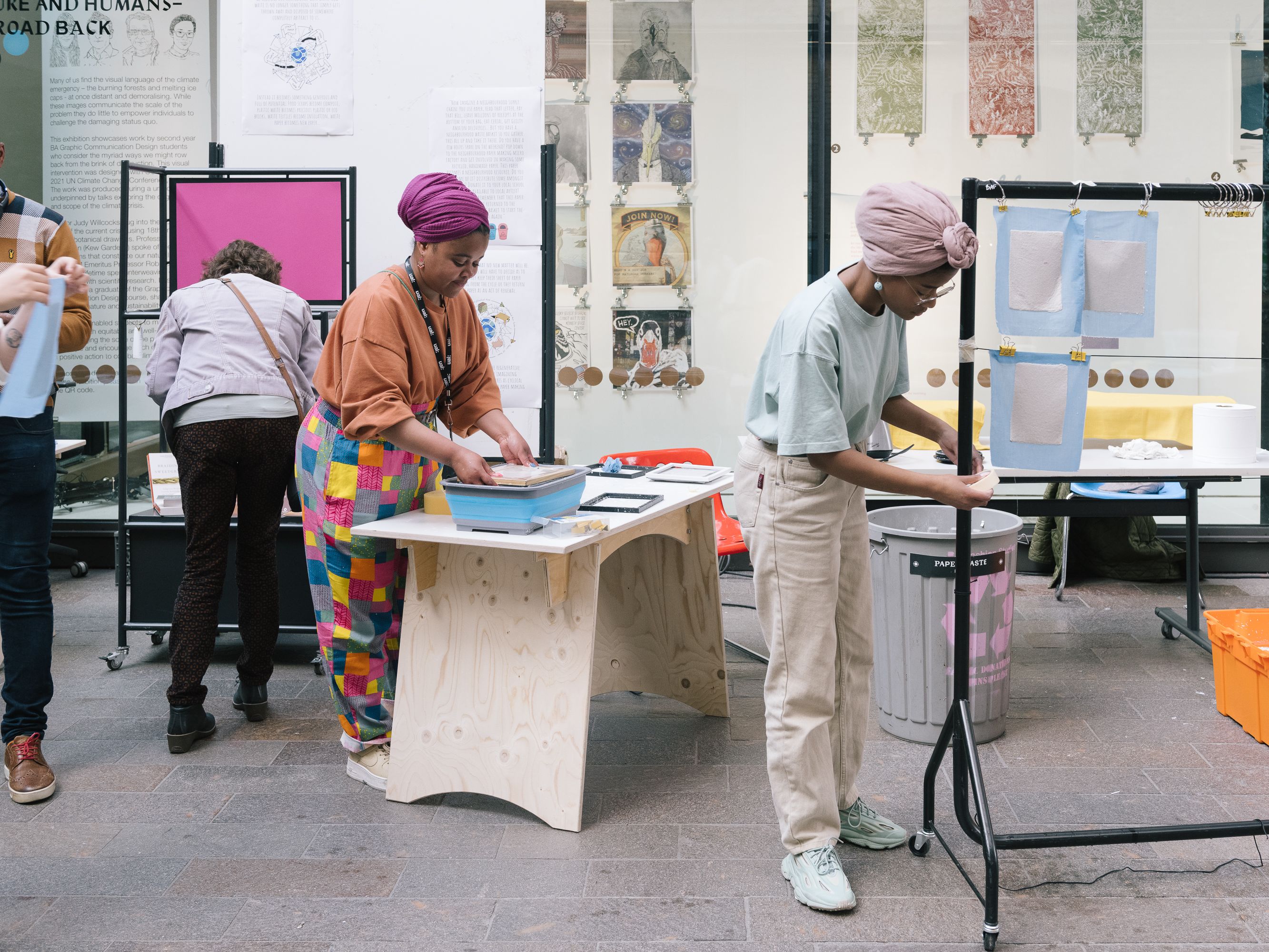 People making and working in the wide open space of the Crossing on CSM's campus. Rails, tables, boxes and artworks are pinned up all around.