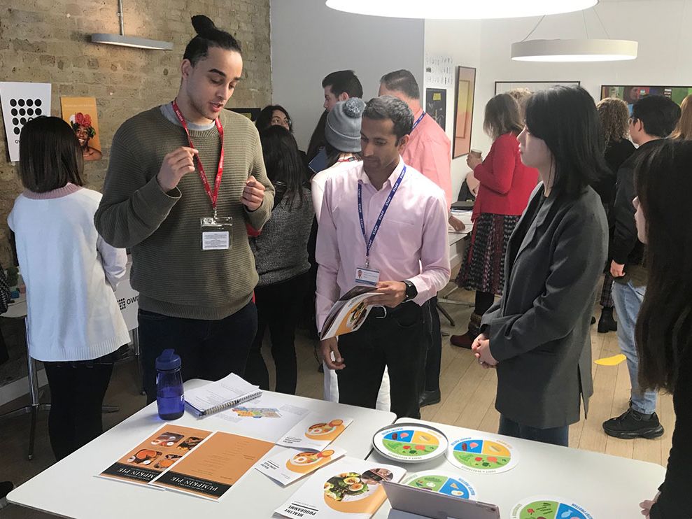 A group of students and audience members peer at project assets.