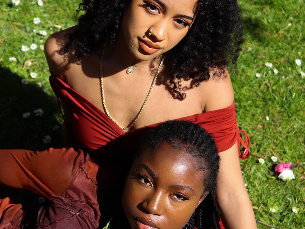 Photograph of two models surrounded by grass and flowers.