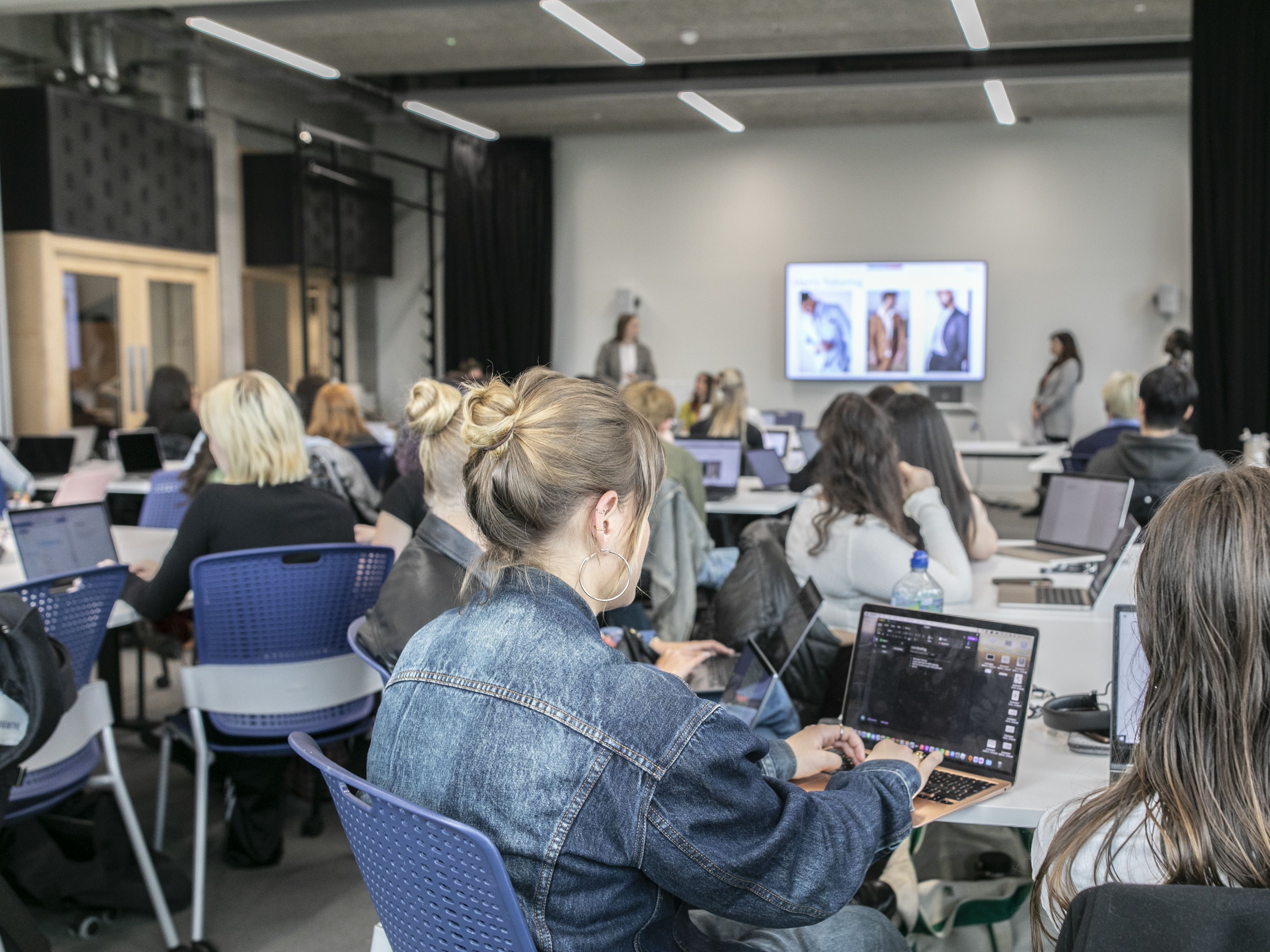 People sat in a classroom with laptops on tables