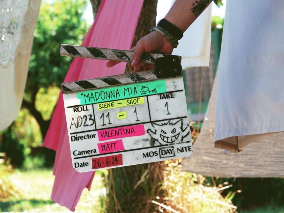 A person holding a clapper board with 'Madonna Mia' written on it