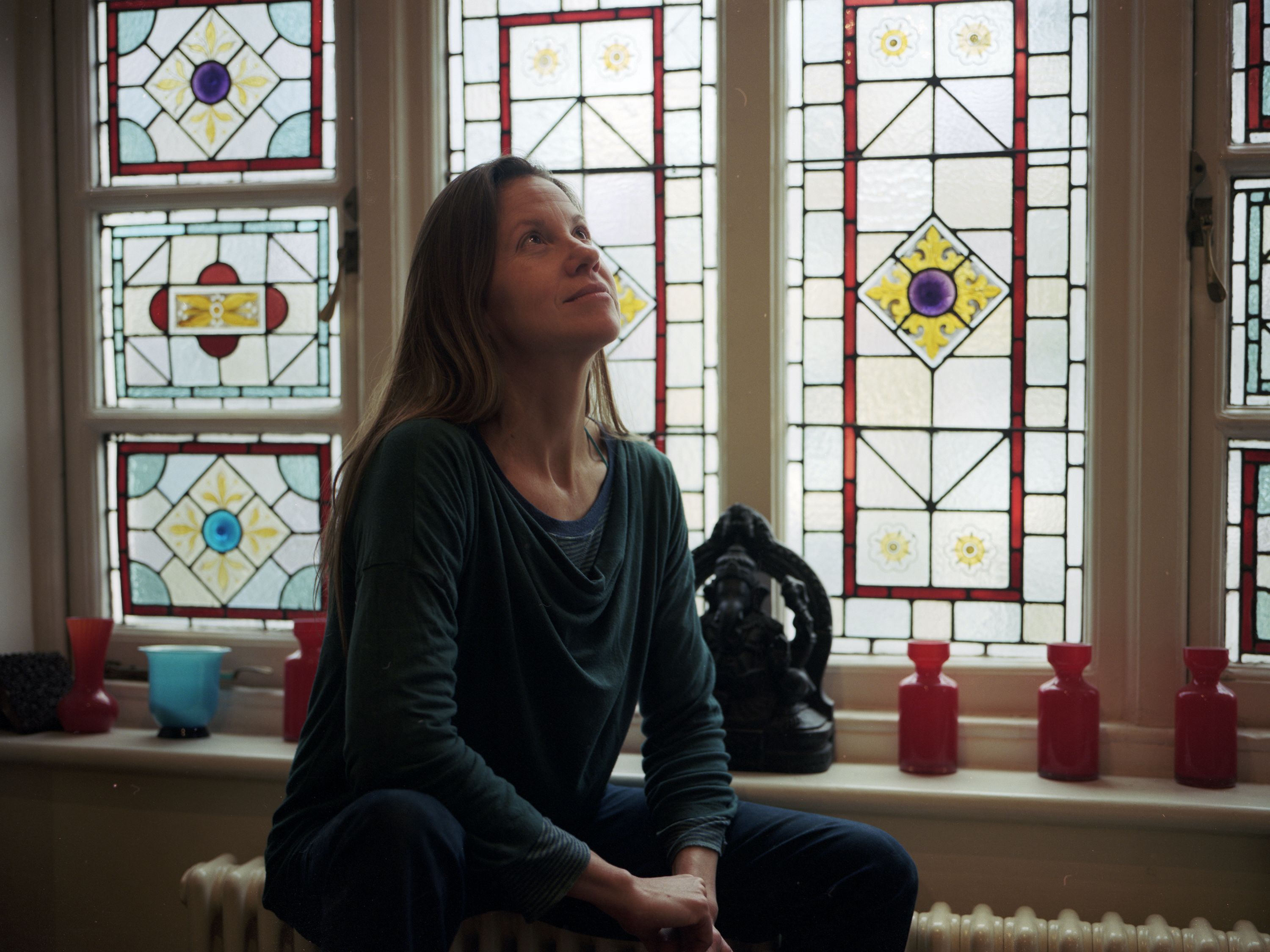A woman sitting near a stain glass window 