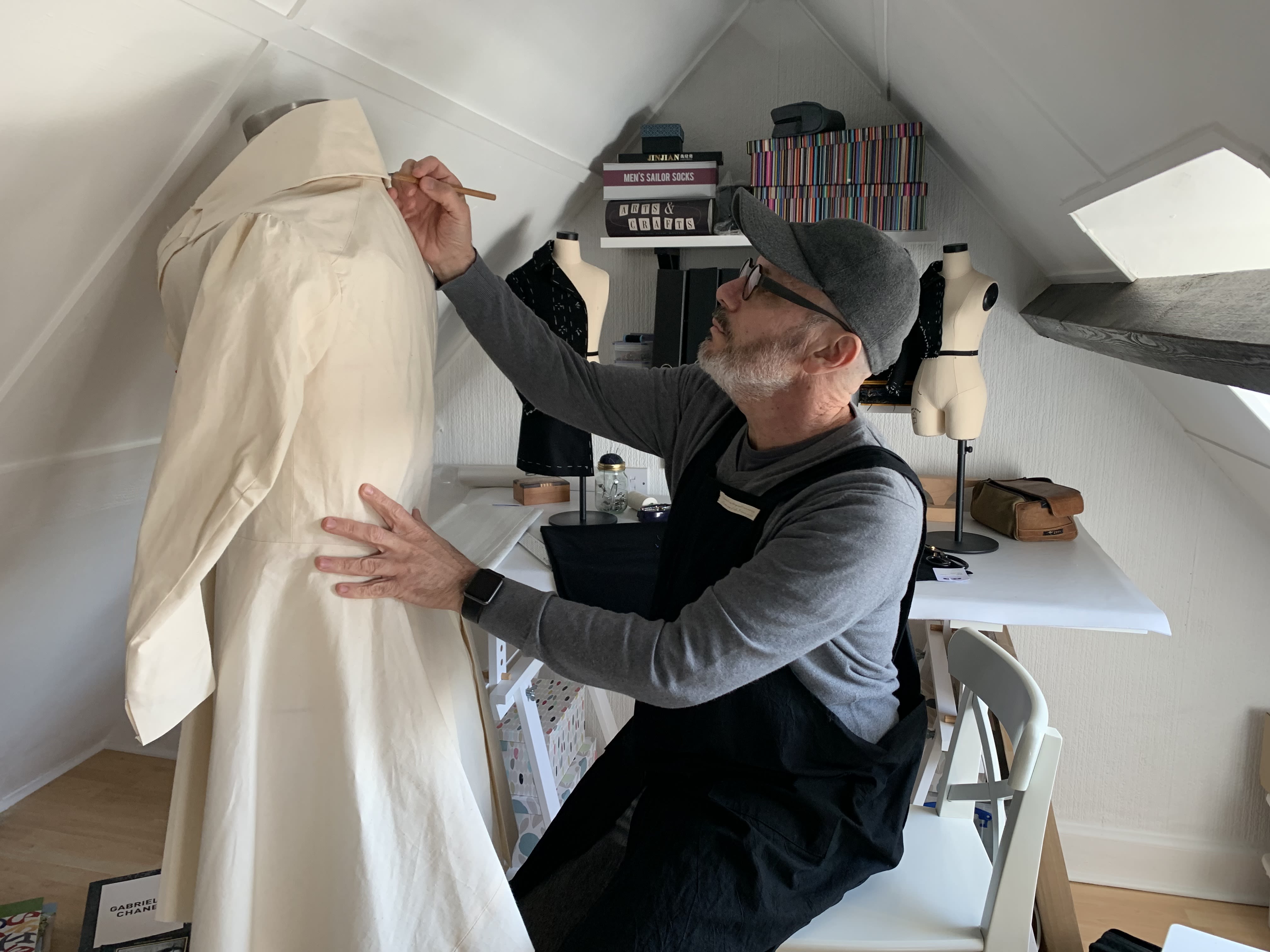 Person marking up a collar on a coat hanging on a mannequin.