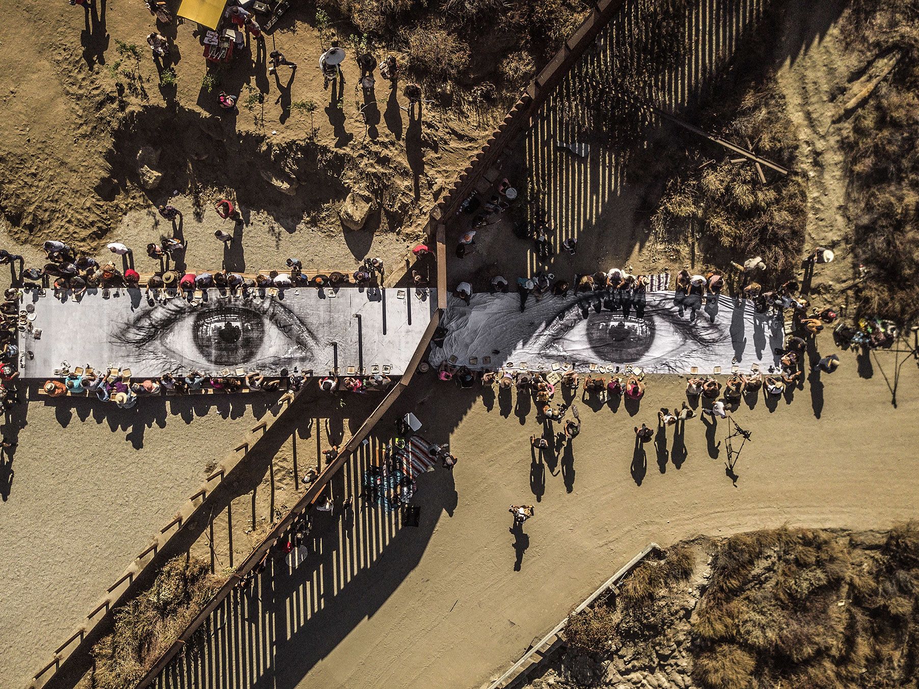 JR (French, born 1983). Migrants, Mayra, Picnic across the Border, Tecate, Mexico - U.S.A, 2017. Installation image. Wheat-pasted poster on table. Copyright: JR.