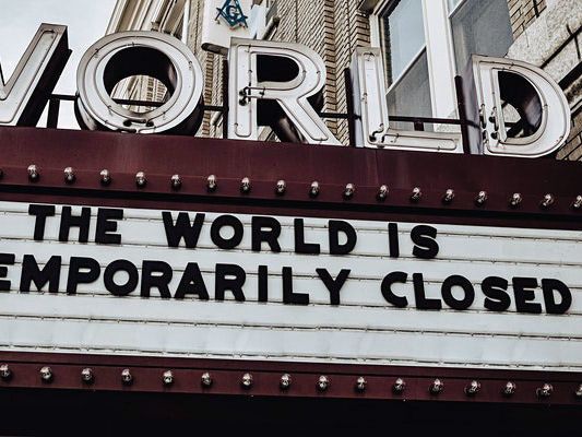 Image depicts a cinema board which reads: 'The world is temporarily closed.'