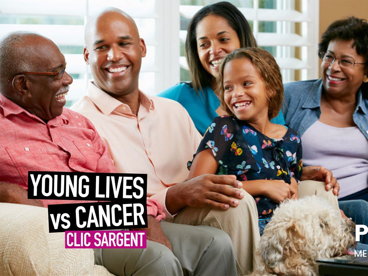 An image of a smiling family sitting on a sofa.
