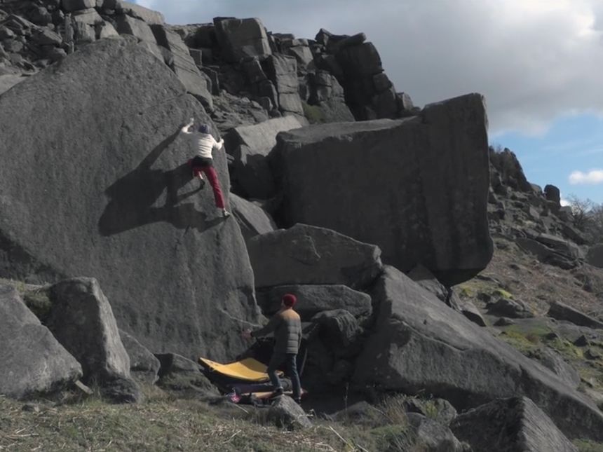 Woman climbs rock-face in mountain.