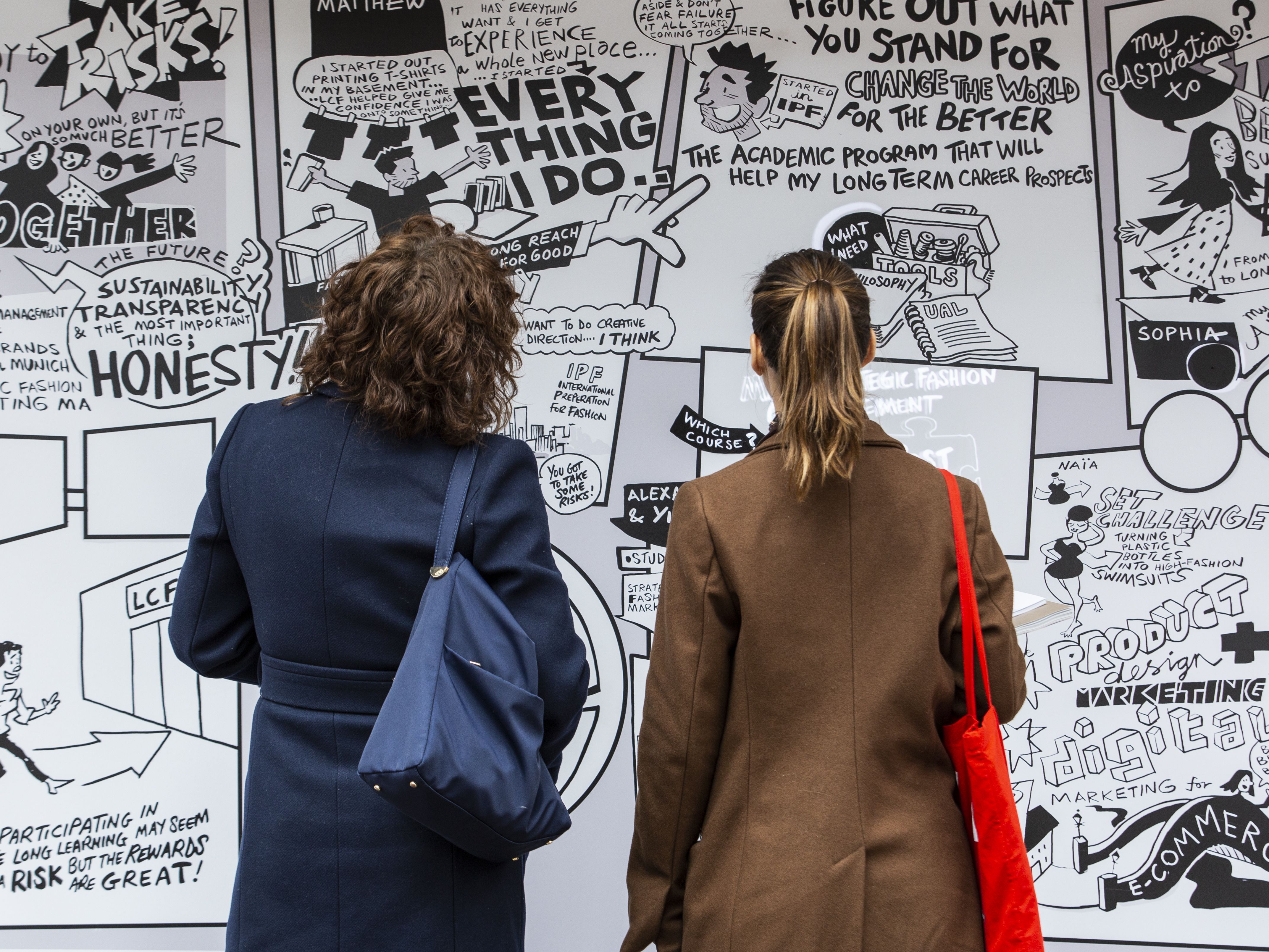 Two people standing up in front of a poster during an exhibition