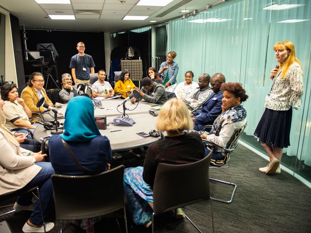 Participants of the Refugee Journalism Project sit in the Guardian Podcast studio with Guardian colleagues.