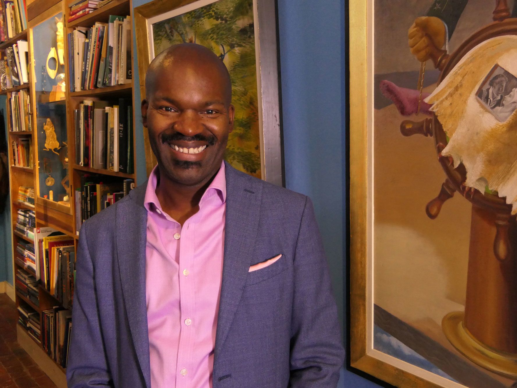 Portrait of David smiling, standing next to a colourful artwork