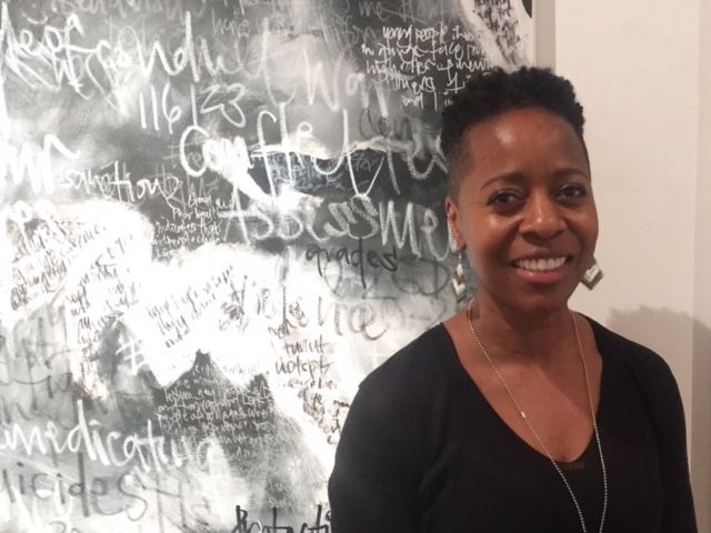  Linett Kamala in front of a black and white painting named 'Courage'
