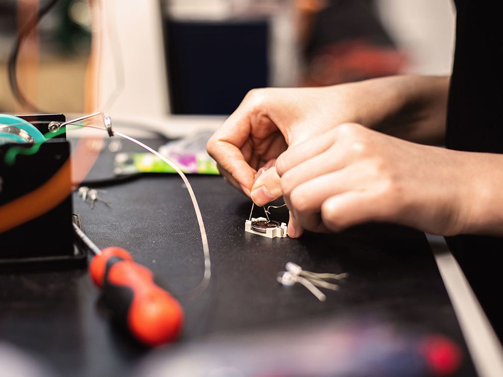 A student uses the soldering bench to work on her project.