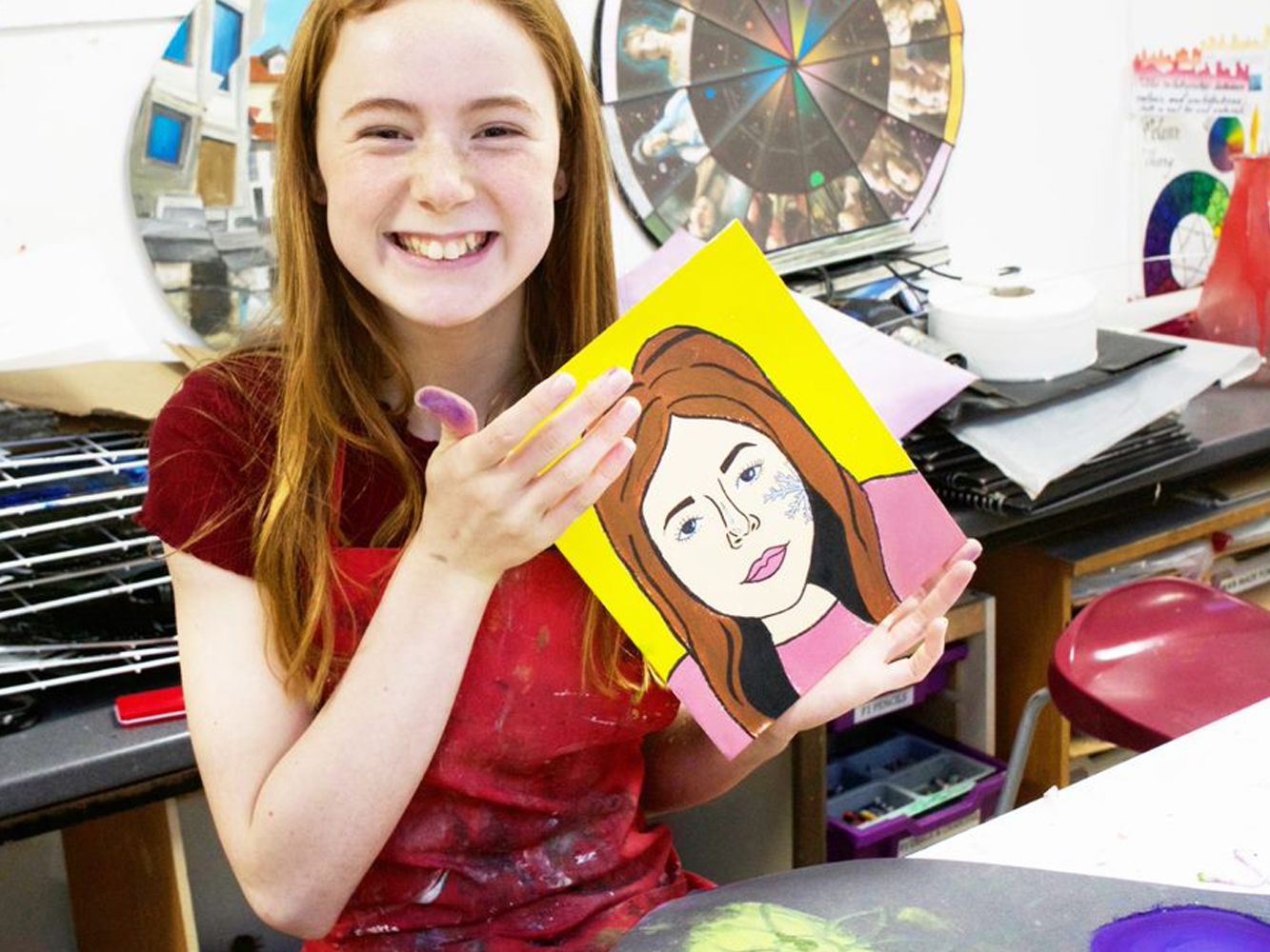 Girl holding up a painted self portrait.