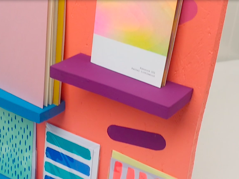 Photograph of shelves constructed from wood, painted in vibrant colours with books and cards resting on the shelves