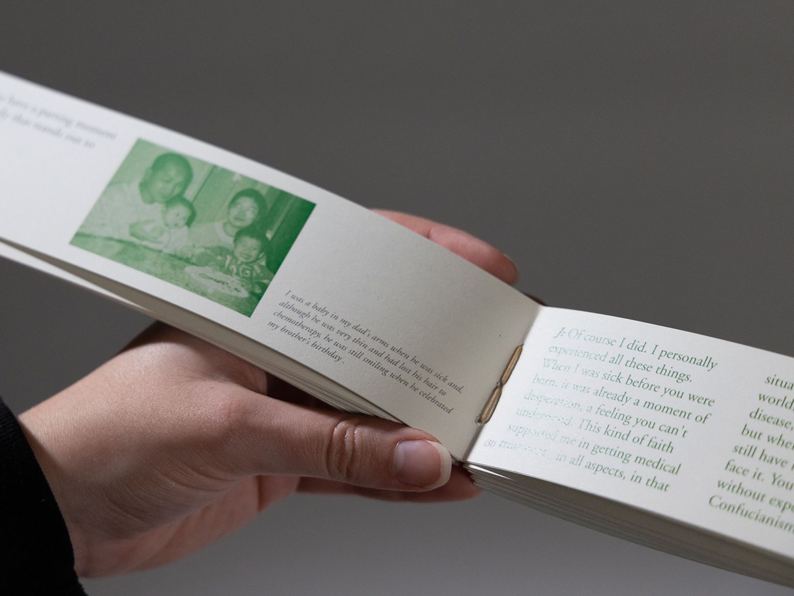 A photograph of someone holding a small, bound book filled with green images.
