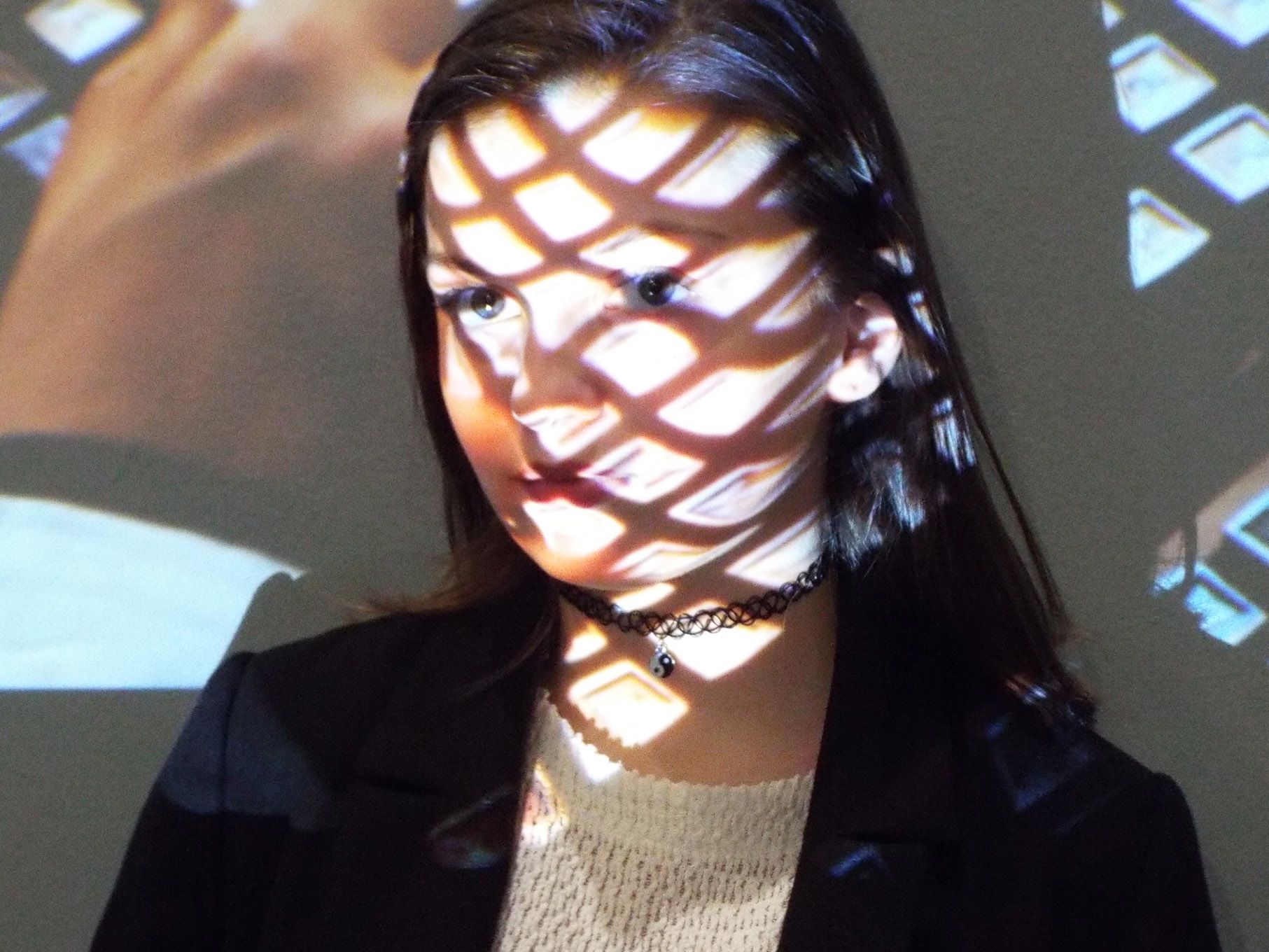 a portrait of a person in front of a projector, projecting a grid pattern onto their face