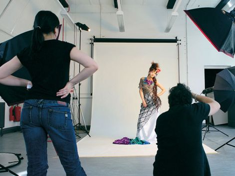 Photography studio with female model in a dress and two photographers
