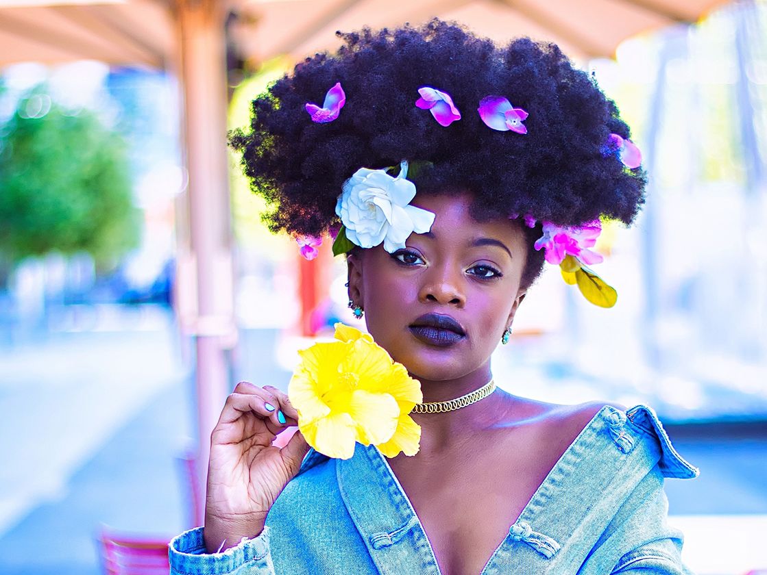 Female model posing with flowers in her hair and denim jacket