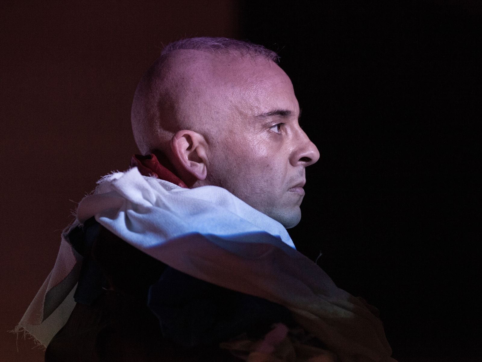 A closeup of Orlando, looking to the side and illuminated by a blue light.