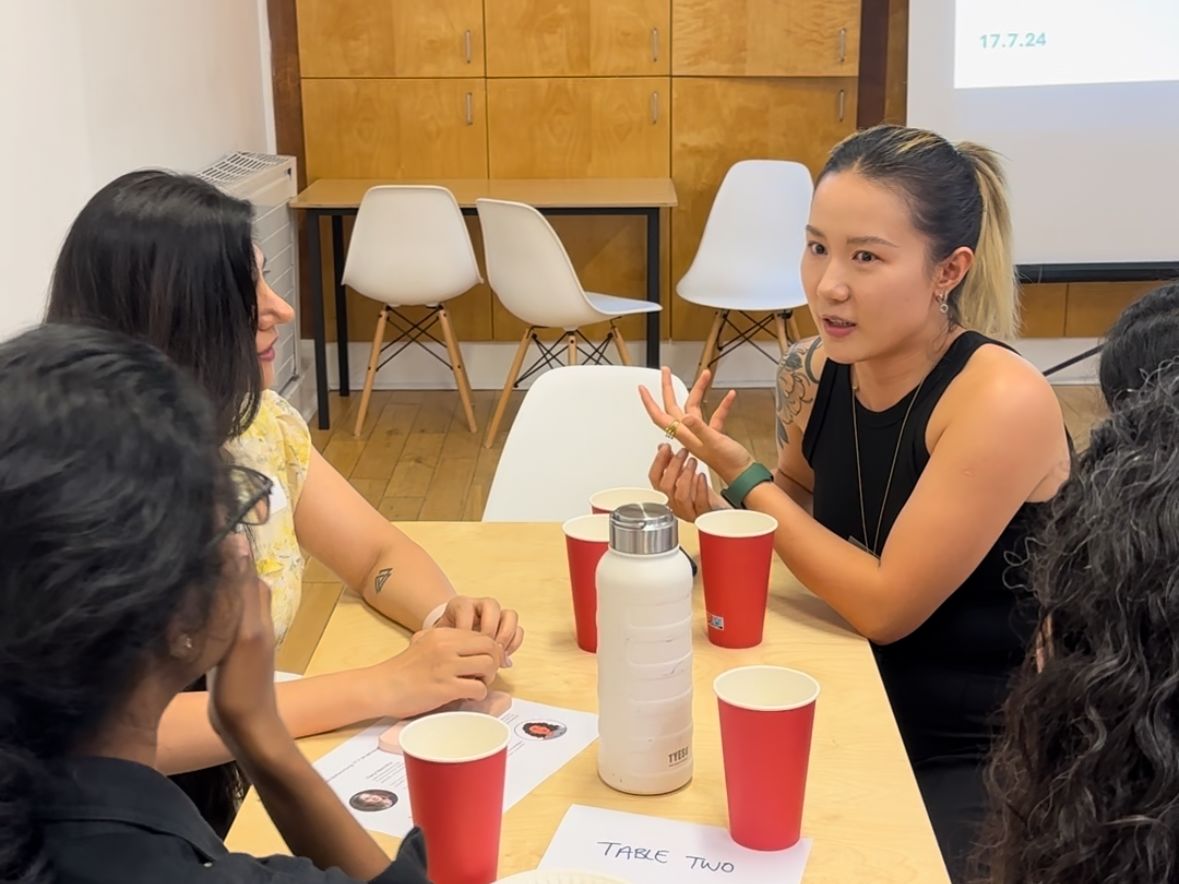 Woman speaks to other women on a table