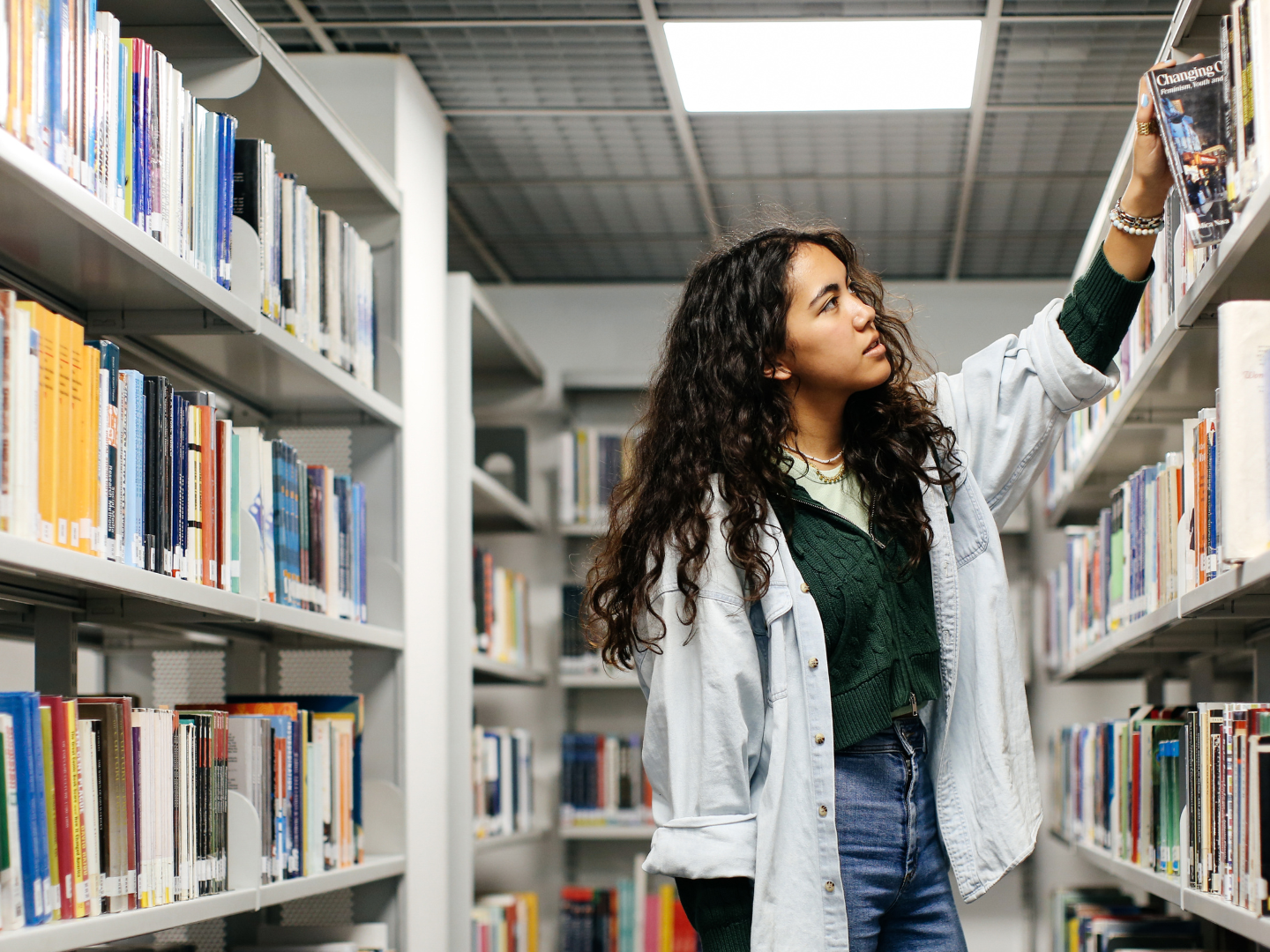 Person finding a book on a shelf in a library