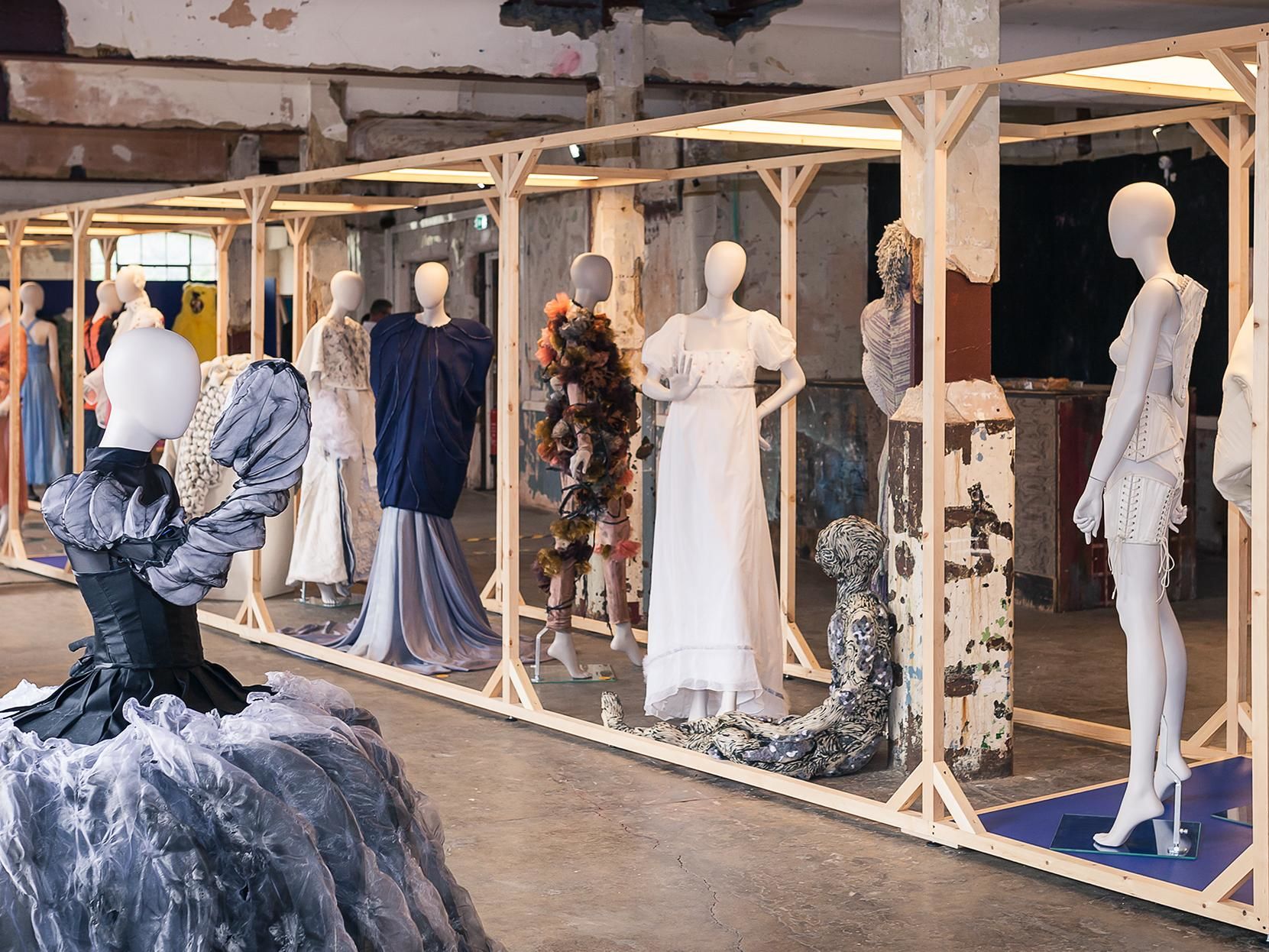 mannequins dressed in a variery of outfits stand in a line, displayed as part of an exhibtion