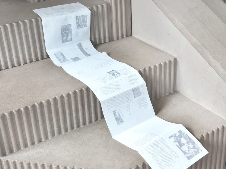 A long piece of paper drapes over a set of steps, folding at the edge of the steps. 