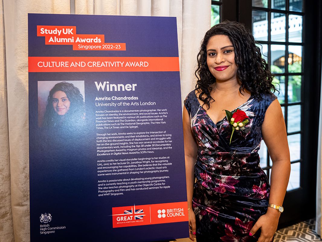 A person smiles beside an information board at an awards ceremony.