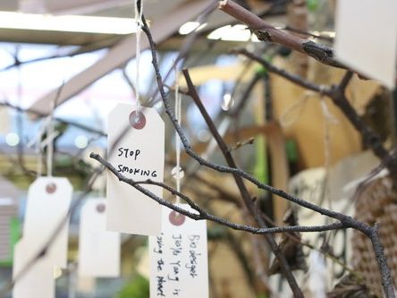 Tree branches with hanging handwritten tags with people's notes written on them