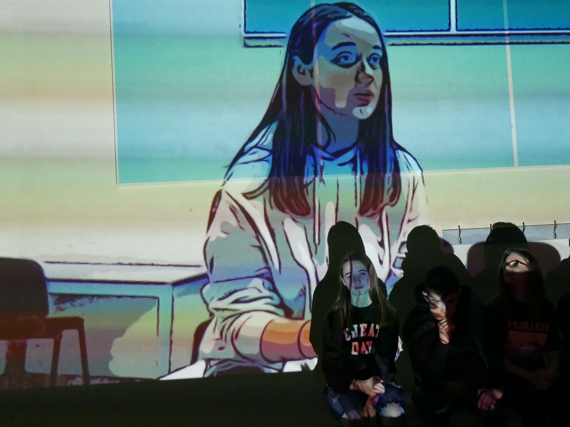 photograph of three students sat against a wall with projection of an image of student in background