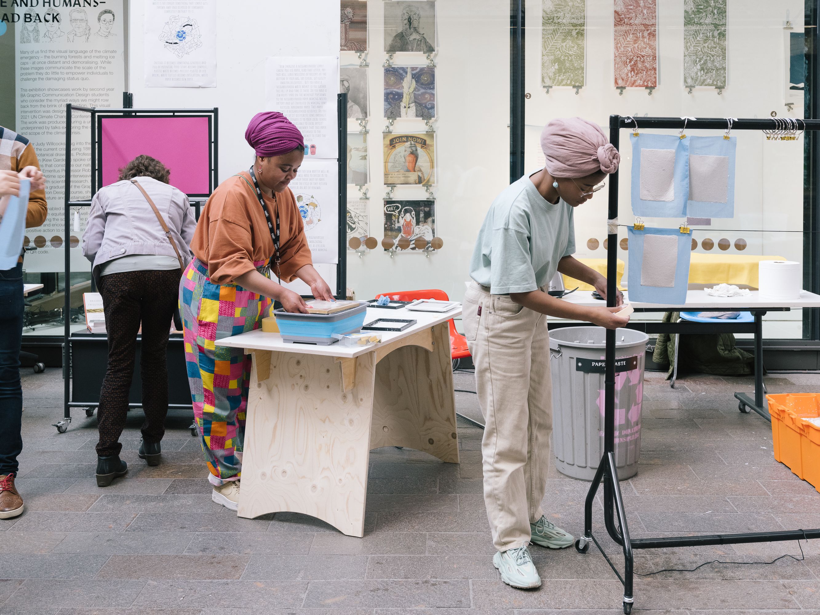 People making and working in the wide open space of the Crossing on CSM's campus. Rails, tables, boxes and artworks are pinned up all around.