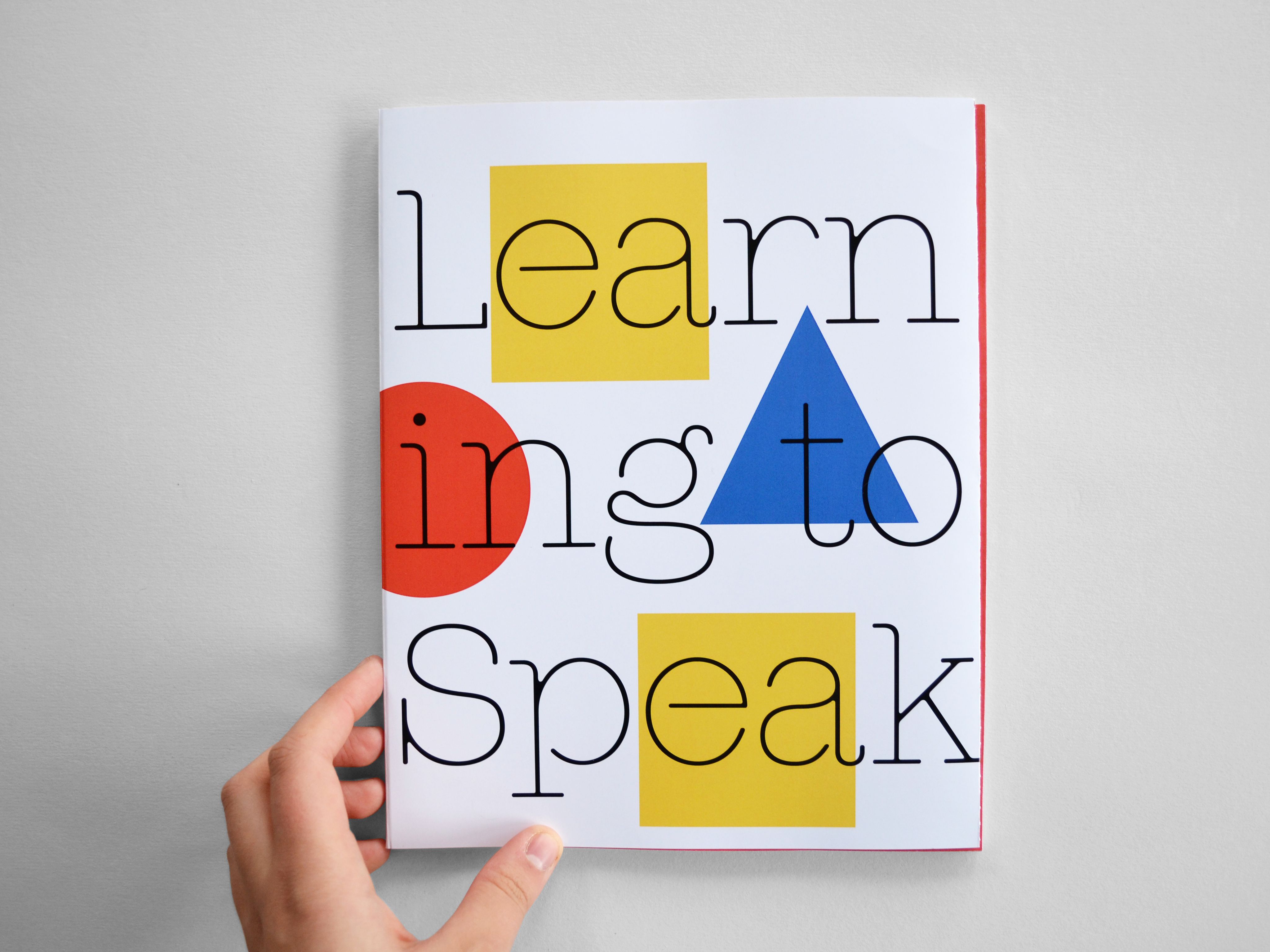 A hand holds small book with colourful shapes. Text reads 'learning to speak' 