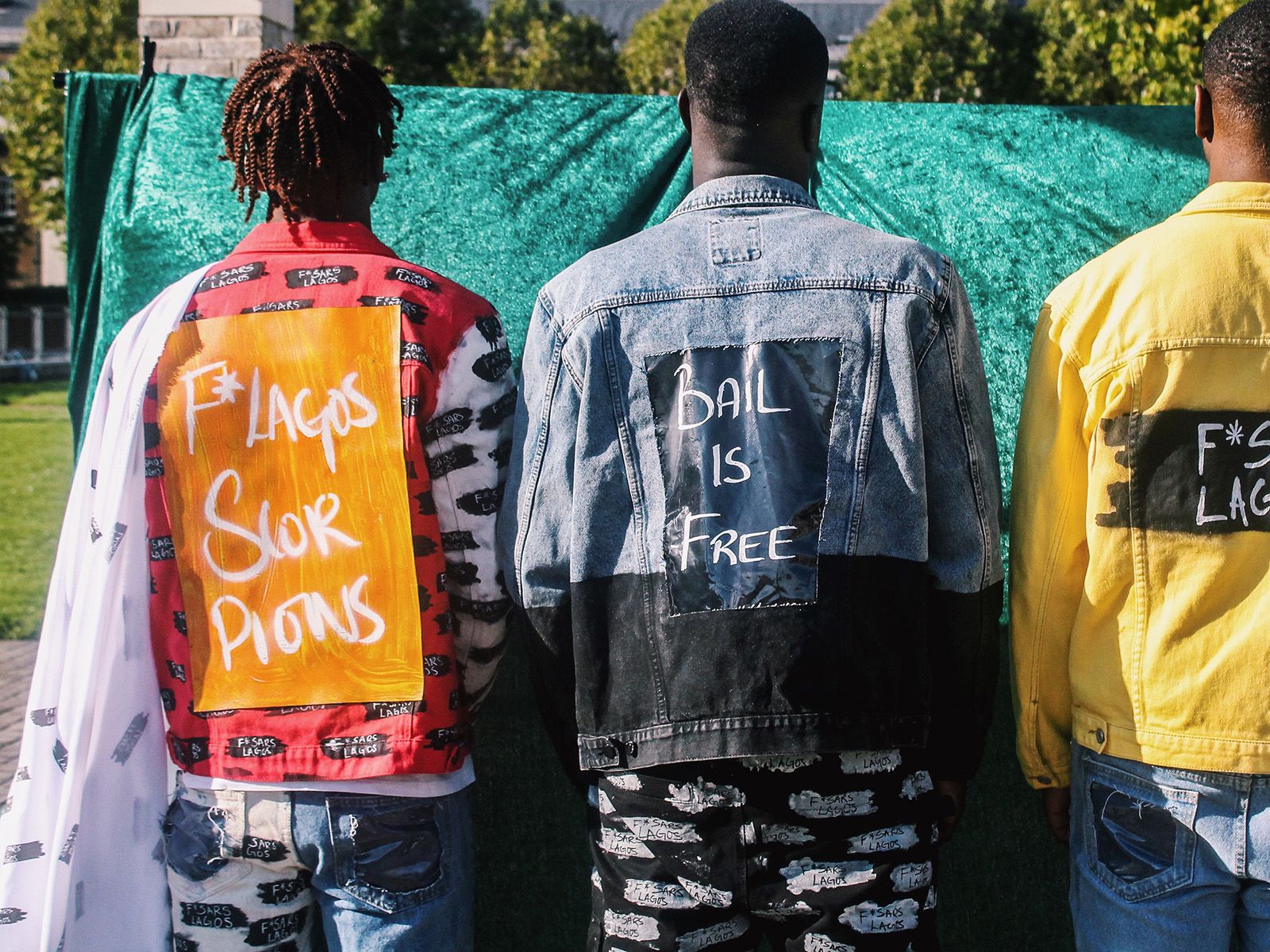 Three men with jackets with 'Bail is free' written on back