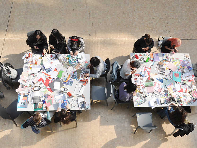 Overhead shot of people sitting at tables making zines.