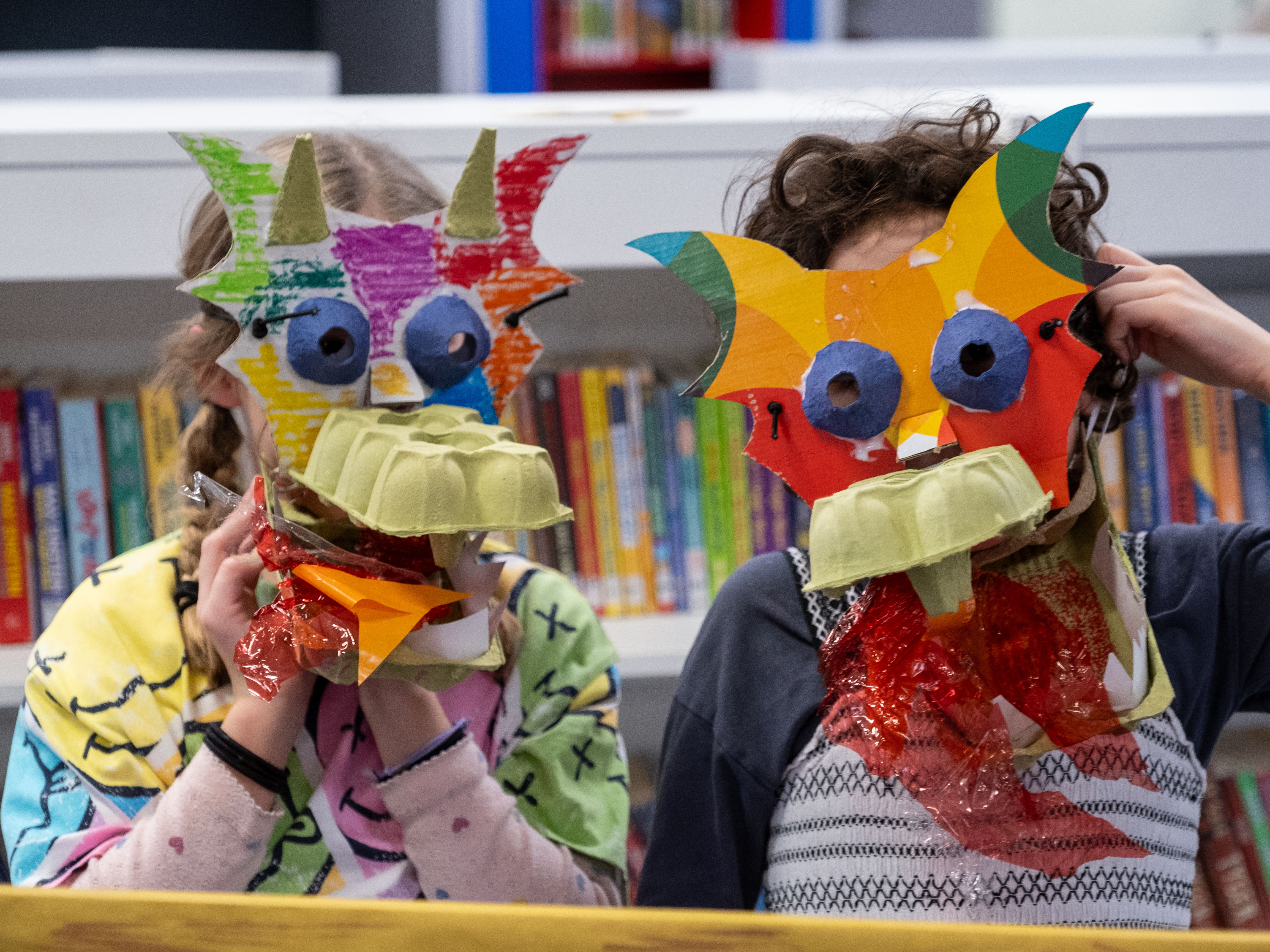 Two children with colourful masks on looking at camera.