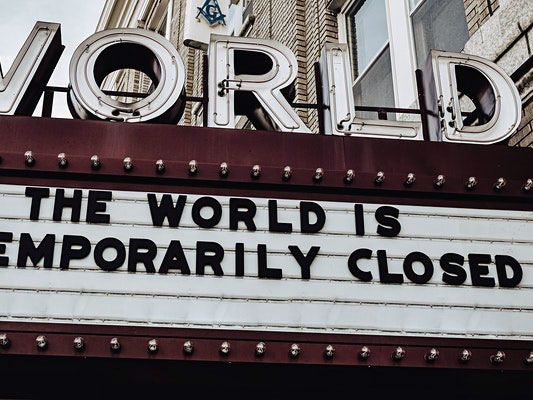 Image depicts a cinema board which reads: 'The world is temporarily closed.'