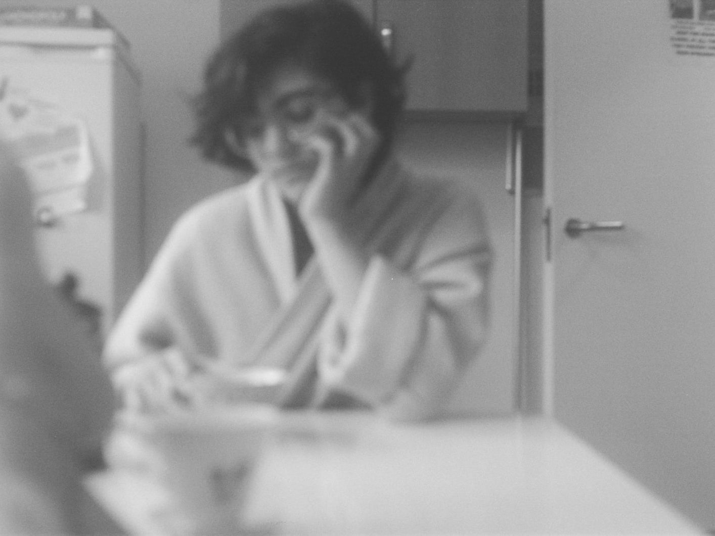 Black and white photograph of a girl sitting at a kitchen table by Monica Santos - BA Fine Art.